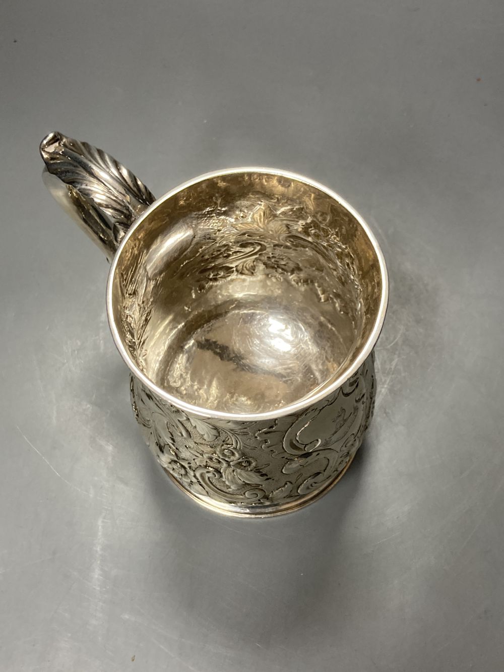 An early George III silver mug, with engraved crest and later embossed decoration, William Shaw II, London, 1764,